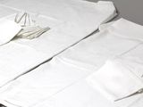 deux serviettes blanches pliées posées sur une table, à côté d'une paire de ciseaux