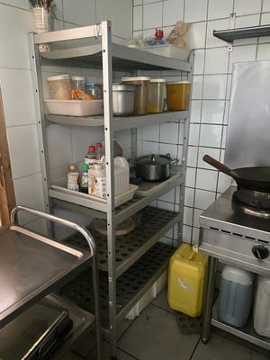 une étagère métallique avec des casseroles et des poêles dans une cuisine