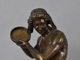 a bronze statue of a man holding a bowl in his hands