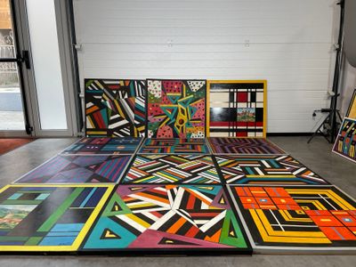 une pièce où il y a plein de tableaux de différentes couleurs posés par terre