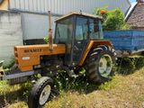 un tracteur garé dans l'herbe près d'un bâtiment