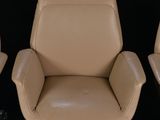 three tan leather office chairs on casteors against a black background