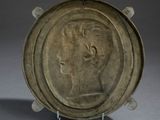 bronze plate with a head of a man on it on a stand