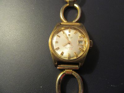 une montre-bracelet en or avec un cadran blanc sur un fond noir