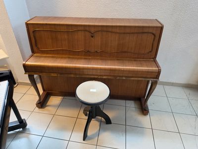 a piano and stool in a room with tile flooring