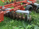 a tractor that is sitting in the grass with a plow behind it