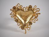 an image of a gold heart shaped brooch with a chain around it
