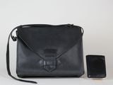 une photo d'un sac à main noir avec un téléphone portable à côté
