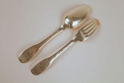 deux cuillères en argent et une fourchette posées sur une table blanche