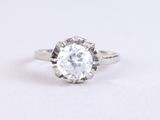 un gros plan d'une bague sertie d'un diamant blanc sur une surface blanche