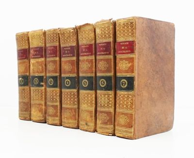 six vieux livres sont alignés sur une surface blanche