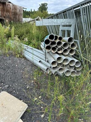 un tas de tuyaux posé par terre près d'une clôture