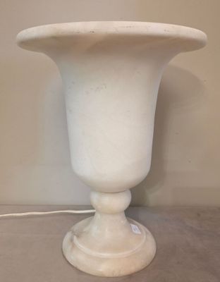 un vase blanc posé sur une table, auquel est attaché un cordon