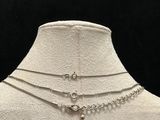 a white mannequin with three different chains and a cross on it