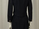 black suit on a mannequin stand against a white curtain