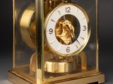 a gold clock with a picture of a woman in a glass case