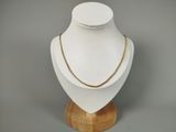 a white mannequin with a gold chain on a wooden stand