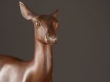 a statue of a deer that is standing in front of a wall