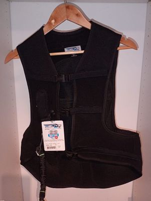 un gilet noir accroché au mur, avec une étiquette dessus