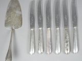 five knives and a spoon sitting next to each other on a table