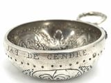 a silver bowl with writing on it on a white surface