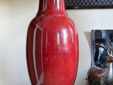 a red vase sitting on top of a table next to a lamp