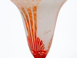 a glass vase with a red base sitting on a white surface