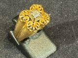 a gold ring with a diamond in it on a black surface