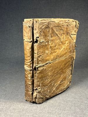 an old book is sitting on a table with a gray background