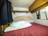 un lit dans une petite chambre avec un couvre-lit rouge