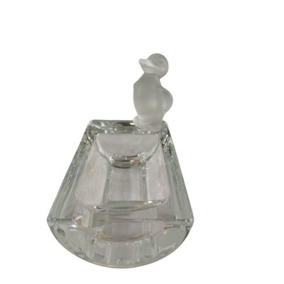 a clear glass perfume bottle with a bird on top of it