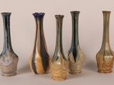 five different colored glass vases lined up in a row