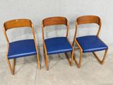 three chairs with blue leather upholstered seats in front of a white wall