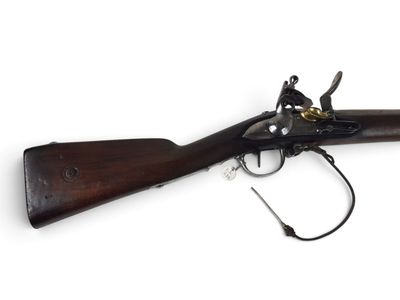 un vieux fusil exposé sur une surface blanche