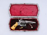 un revolver argenté dans un étui rouge posé sur une surface blanche