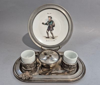 a silver tray with cups and saucers and a plate with a picture of a man on it