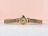 gros plan d'une montre-bracelet en or sur une surface blanche