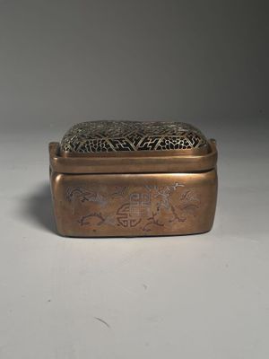 an old brass box with a design on it on a white surface