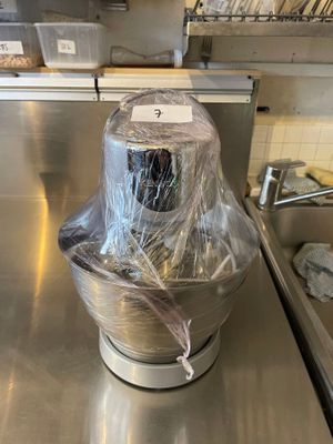 stainless steel counter top with a blender wrapped in plastic and a sink in the background
