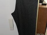 grey pants hanging on a hanger in a room with a white wall
