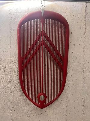 a red radiator grill hanging on a white wall