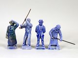 trois figurines représentant des hommes portant un chapeau et une canne, posées sur une surface blanche