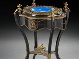 une table ancienne sur laquelle est posé un verre bleu