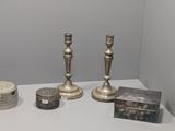 trois bougeoirs en argent et une boîte posés sur une table blanche