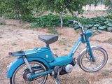 un cyclomoteur bleu garé dans l'herbe