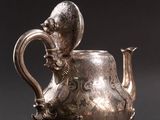 two silver teapots with handles and handles on a black surface