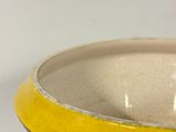 a yellow and black bowl sitting on a white table