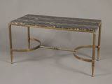 une photo d'une table basse au plateau en marbre et aux pieds en laiton