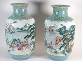 paire de vases chinois ornés de personnages, posés sur un socle blanc
