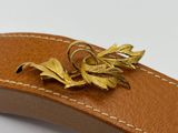 a gold leaf brooch on a brown leather belt